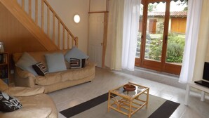 Un salon avec un canapé beige, une table basse en bois et un escalier.
