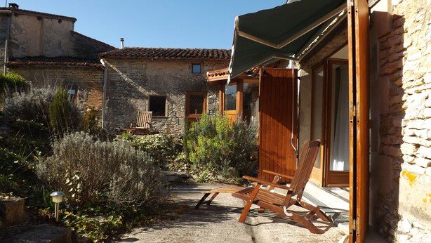 Un bâtiment rustique en pierre, doté d’une porte en bois et d’un auvent vert.
