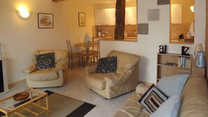 Un salon chaleureux avec un canapé, des fauteuils, une table basse et un coin repas comprenant une table et des chaises.