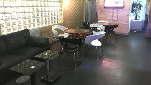 A modern lounge area with a sofa, a glass coffee table, and a round table with chairs. - Zaaz Hotel (Lagos)