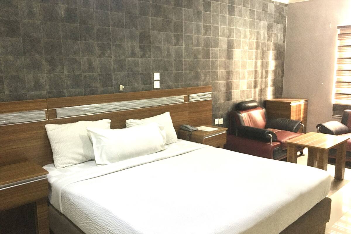 Una habitación de hotel con una cama grande, un cabecero de madera, un escritorio y un sillón de cuero.