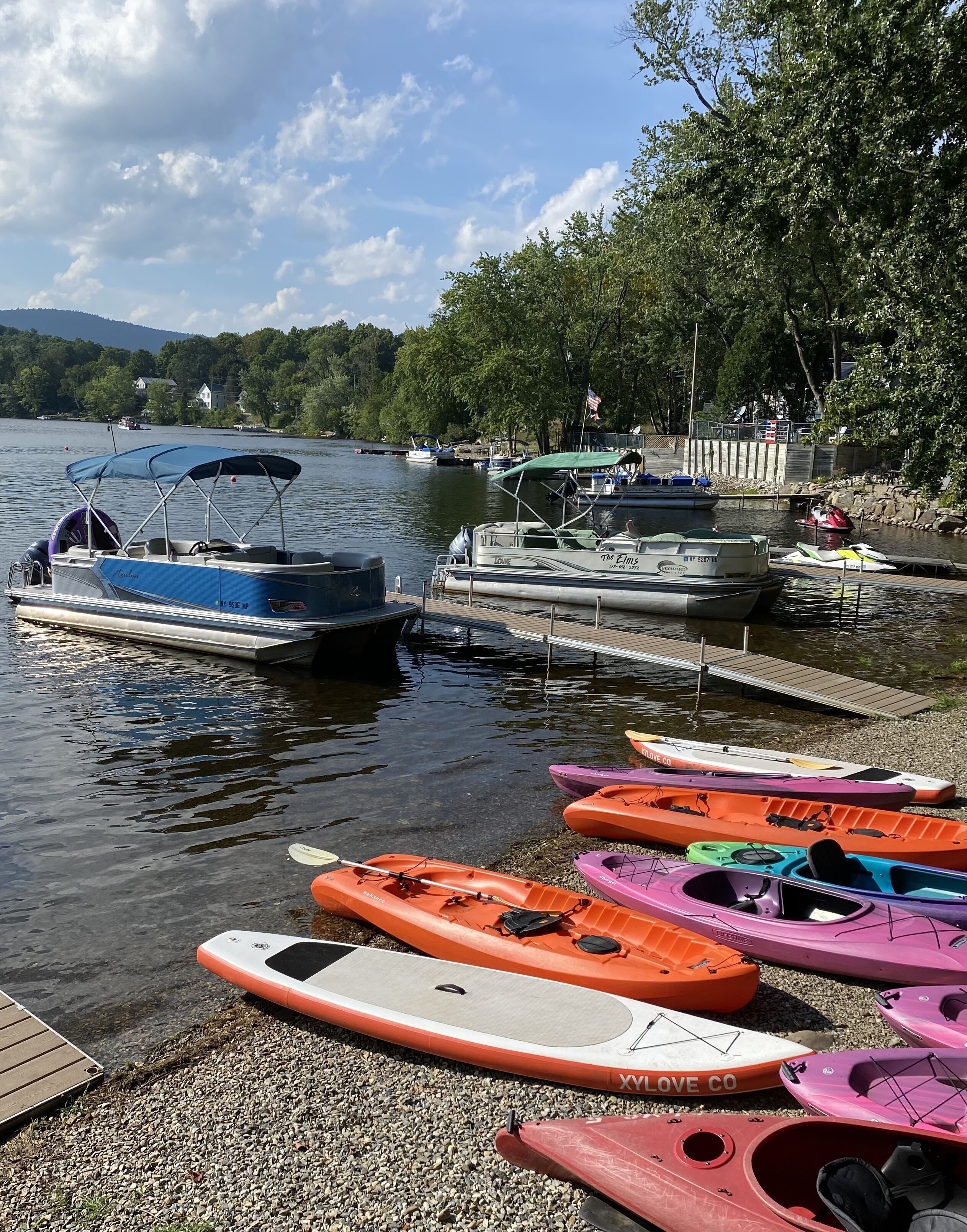 Une jetée au bord du lac, avec des kayaks et un bateau.
