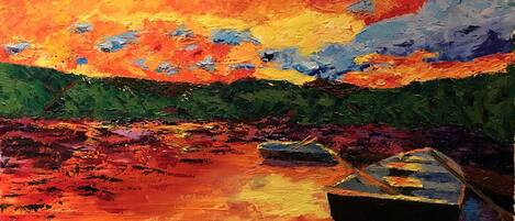 A vibrant sunset scene with boats on a reflective water surface.