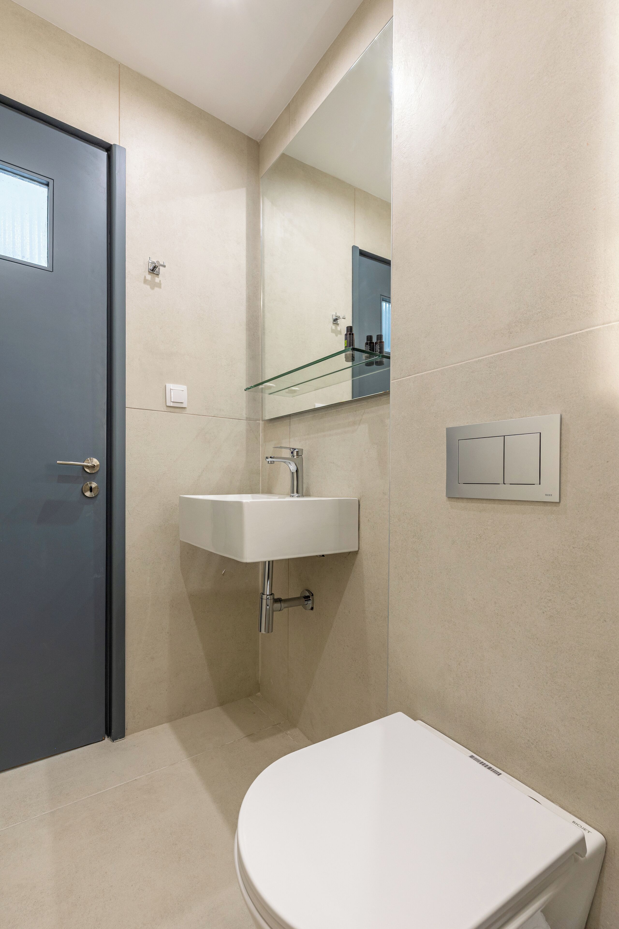 A modern bathroom with a toilet, sink, and mirror.