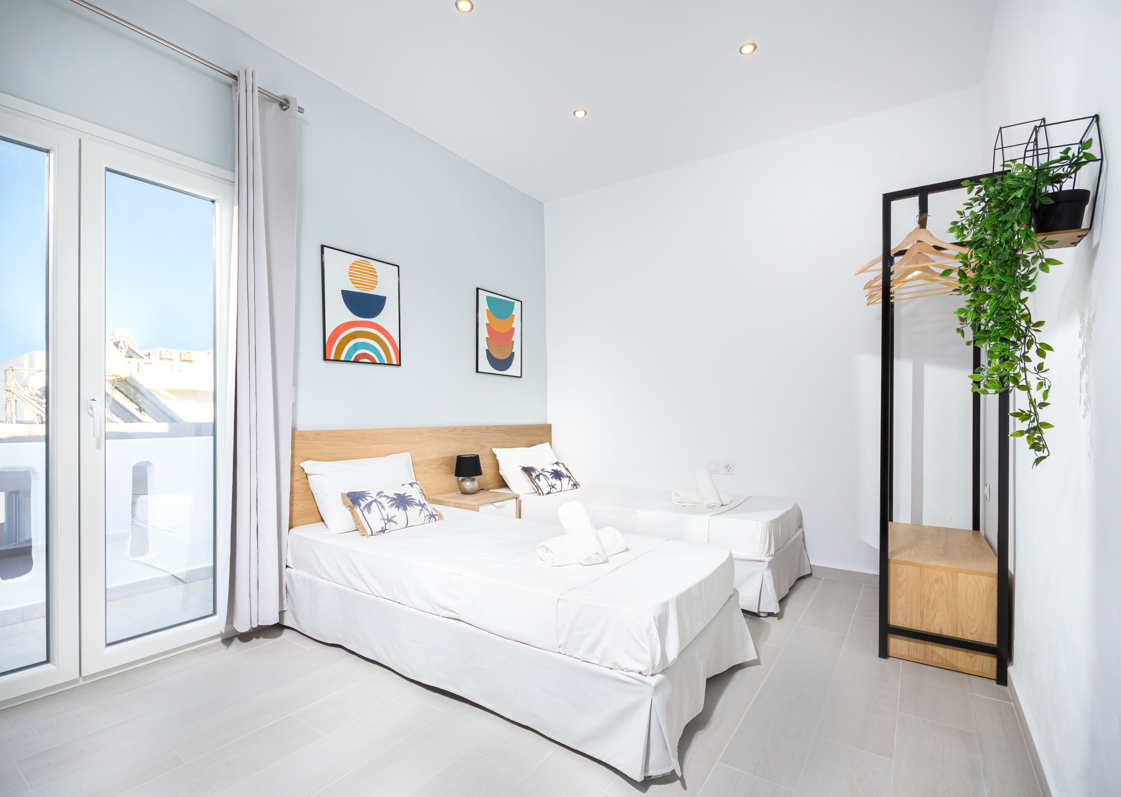 Una habitación de hotel moderna con dos camas, un ventanal grande y un balcón.