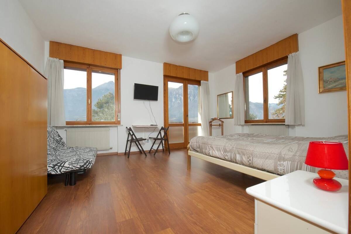 A bedroom with a bed, a desk, a chair, and a TV.
