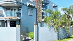 Une maison moderne à deux étages, dotée d’un balcon, d’une façade en pierre et d’une entrée sécurisée par un portail.
