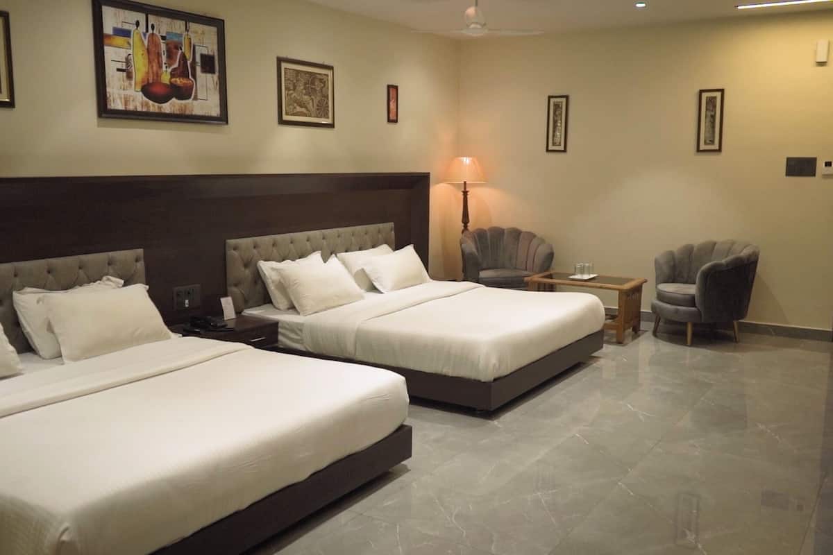 Une chambre d’hôtel avec deux lits, un bureau, une chaise et des œuvres d’art accrochées aux murs.