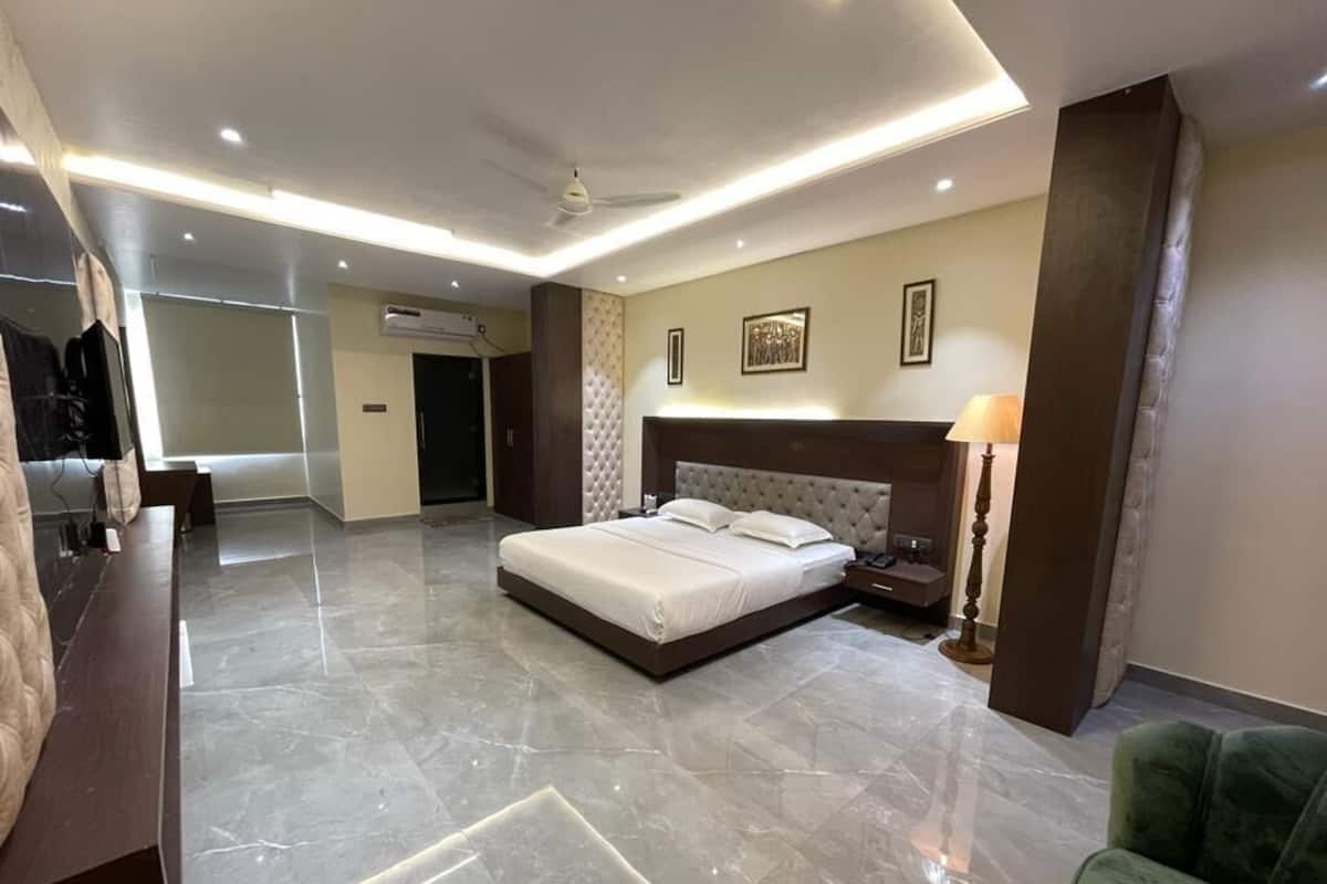 Une chambre d’hôtel moderne avec un grand lit, un bureau et un fauteuil vert.
