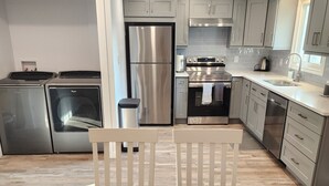 A modern kitchen with stainless steel appliances, white cabinetry, and a wooden dining table. - Walk to the Falls & Attractions!
Modern, clean & comfortable 4 bedroom house (Niagara Falls)