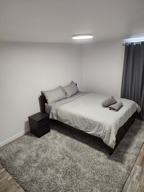 A bedroom with a bed, a nightstand, a rug, and a ceiling light.