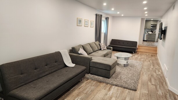 A modern living room with a grey sectional sofa, a smaller sofa, and a coffee table. - Walk to the Falls & Attractions!
Modern, clean & comfortable 4 bedroom house (Niagara Falls)