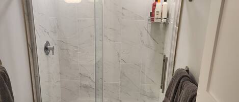 Un baño moderno con ducha de vidrio, inodoro y tocador con espejo.