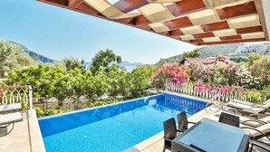 Ein Poolbereich mit Bergblick, umgeben von Grünpflanzen und Blumen.