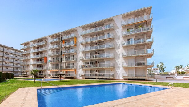 A multi-story residential building with balconies, a swimming pool, and a well-maintained lawn. - MARINES MESTRAL  2 5 Roses (Rosas / Roses)