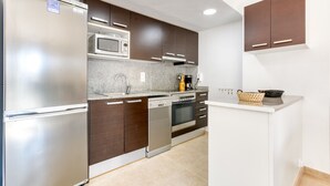 A modern kitchen with stainless steel appliances, dark wooden cabinets, and a granite countertop. - MARINES MESTRAL  2 5 Roses (Rosas / Roses)