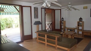 Amplia sala de estar con un banco de madera, una mesa y ventiladores de techo.