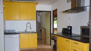 Una cocina con gabinetes amarillos, lavavajillas, horno y estufa.