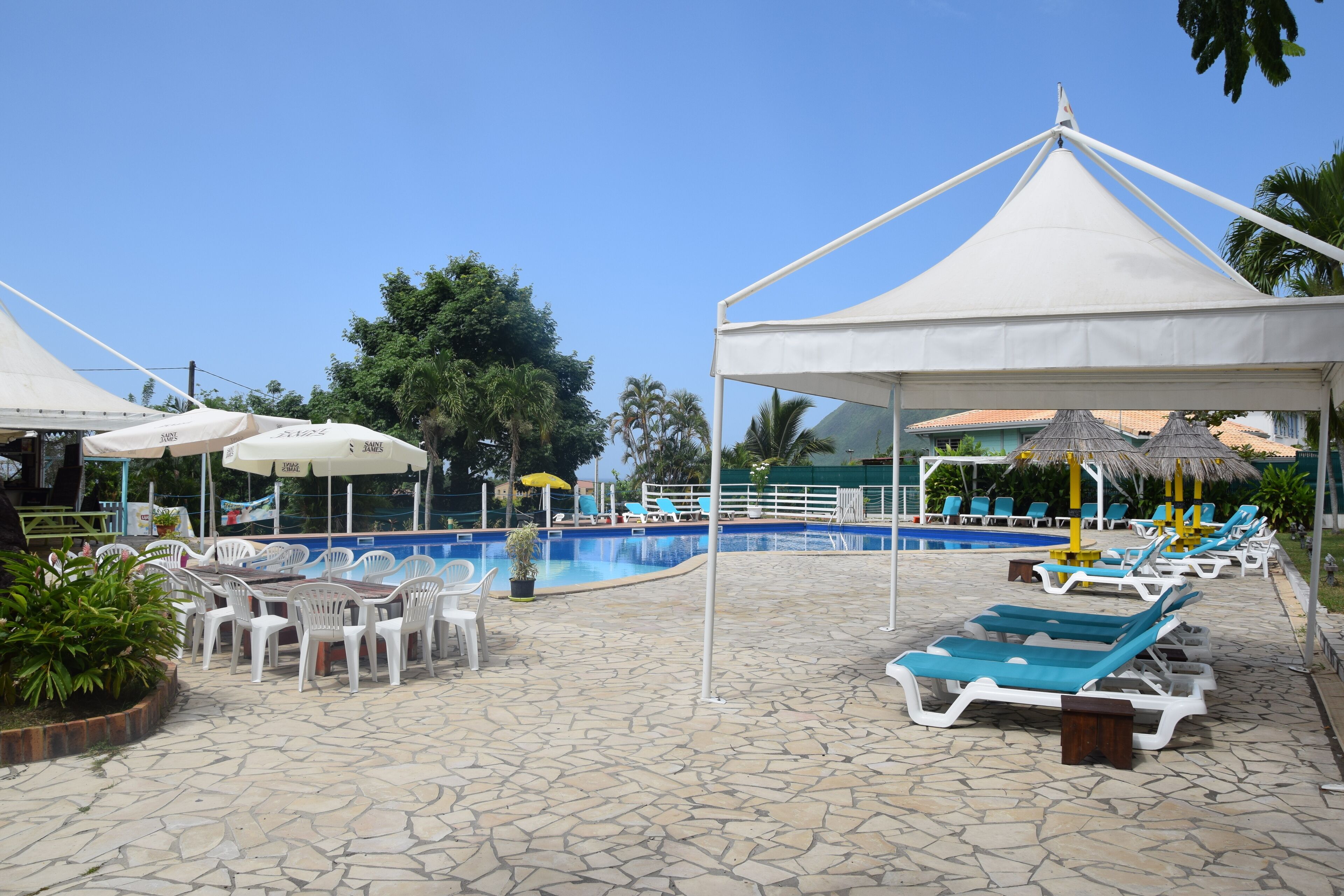 Un espace aménagé au bord de la piscine, avec des chaises longues, des parasols et une piscine.