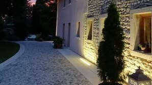 Edifici de pedra amb un carrer empedrat i un arbre petit en una testosa.