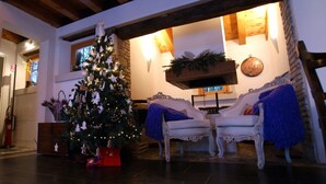 Un saló acollidor amb un arbre de Nadal decorat, una llar de foc i una zona de seients confortable.