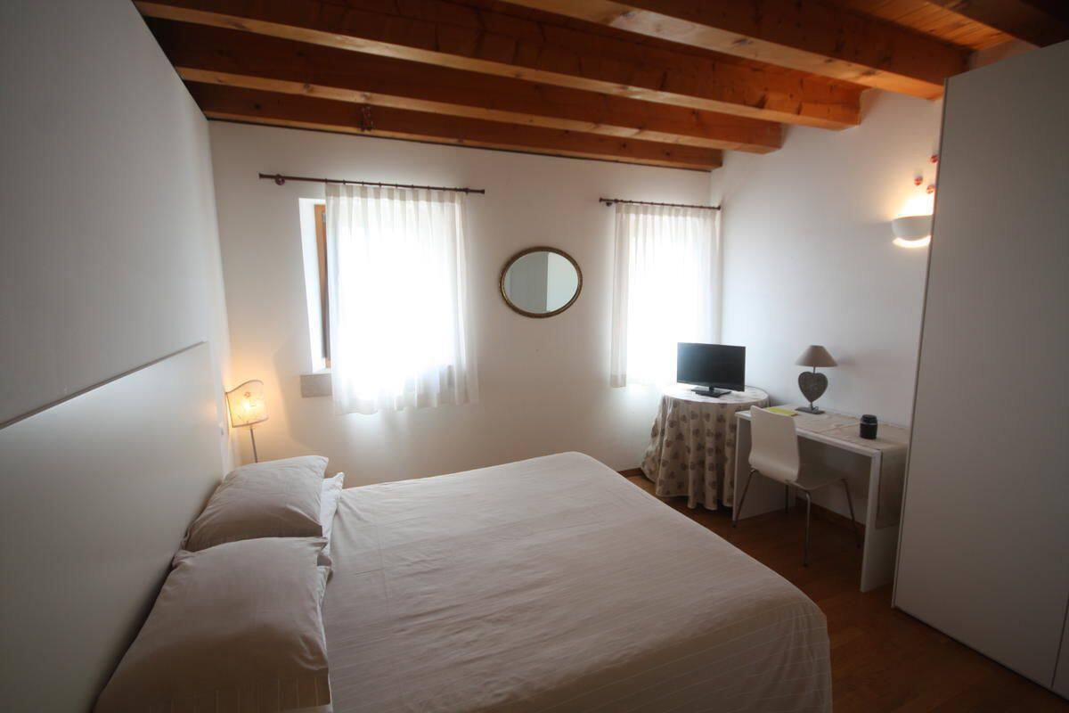 A bedroom with a bed, a desk, a chair, a television, and a mirror.