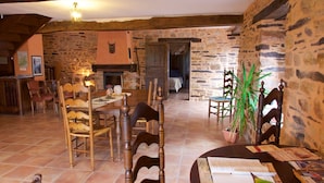 A rustic dining area with stone walls, wooden furniture, and a fireplace. - Hôtel Jouet (Plelan-le-Grand)