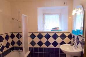 A bathroom with a shower, a sink, and a window above the sink. - Hôtel Jouet (Plelan-le-Grand)