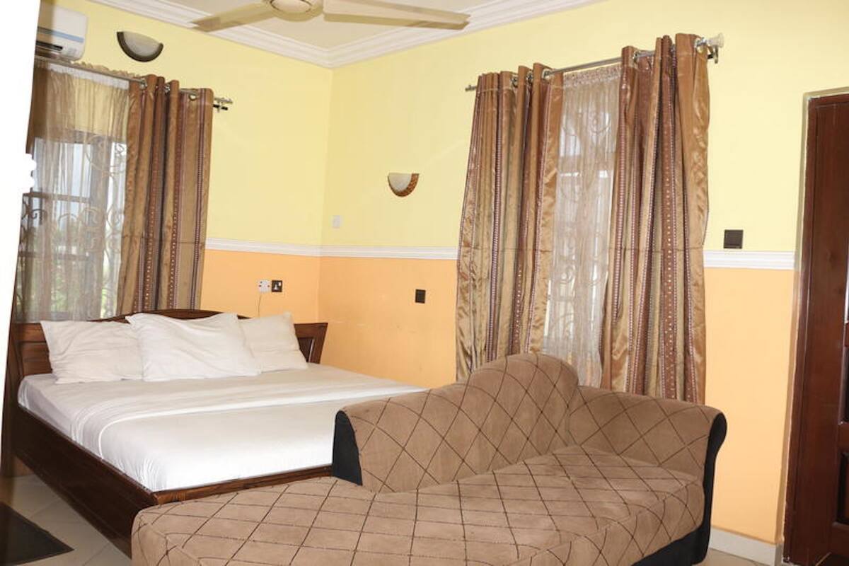 A hotel room with a bed, a sofa, and curtains.