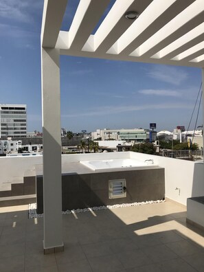 Enjoy panoramic views from this rooftop space with a flat, tiled floor and shaded seating area.