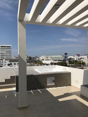 Enjoy panoramic views from this rooftop space with a flat, tiled floor and shaded seating area.