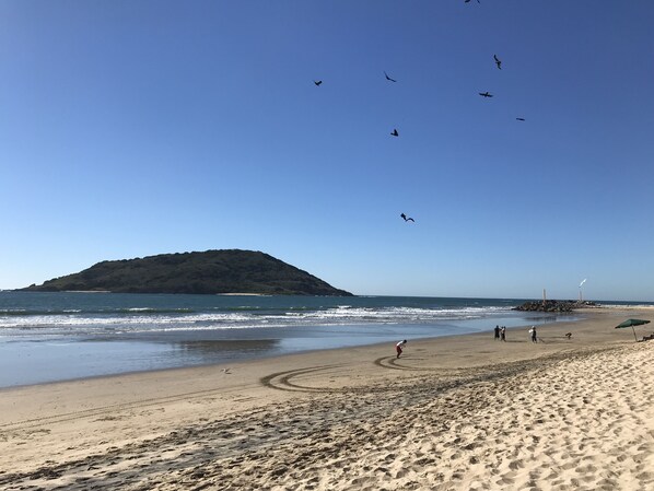 Enjoy a serene beach experience with calm seas and a distant island.