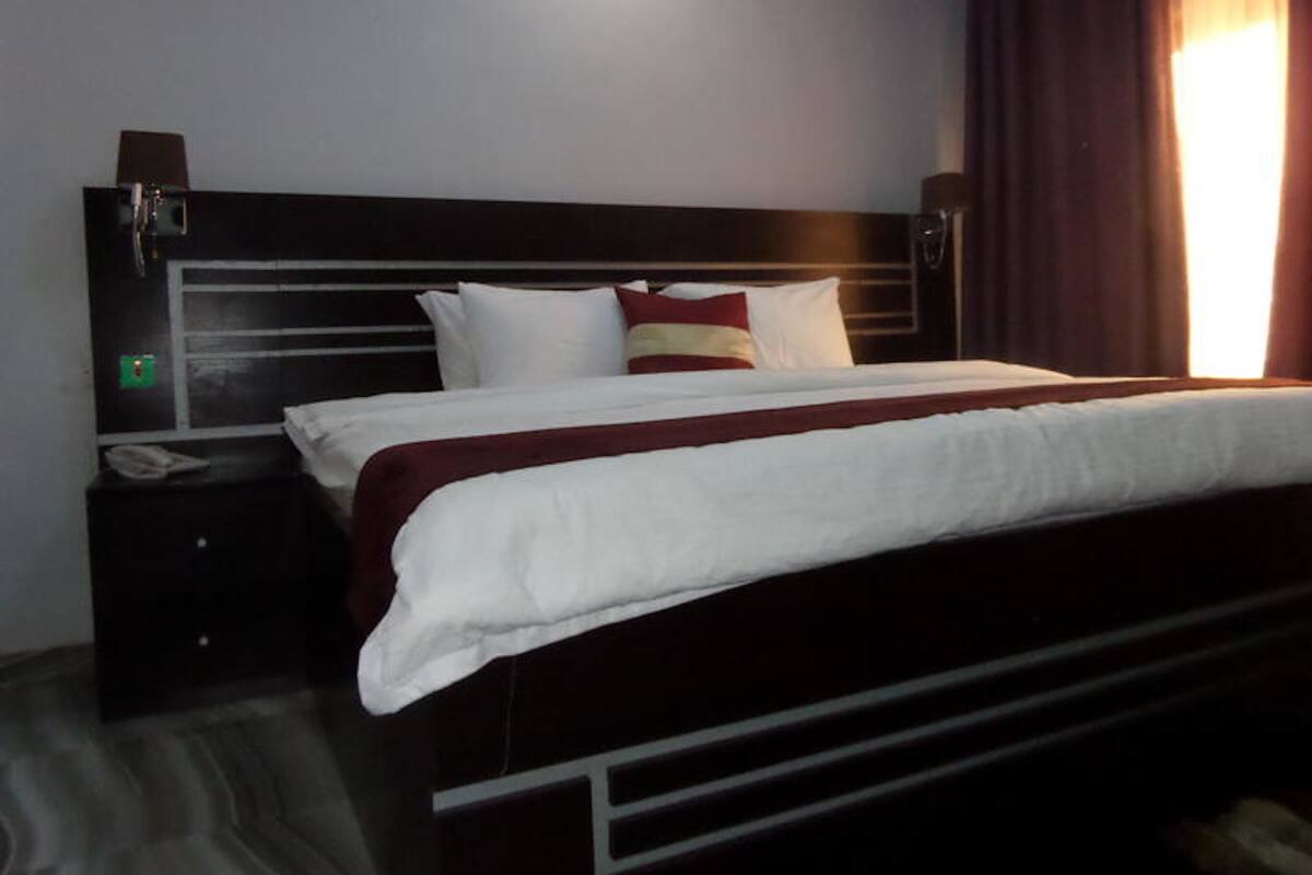 A hotel room with a large bed, a bedside table with a phone, and a headboard with built-in speakers.