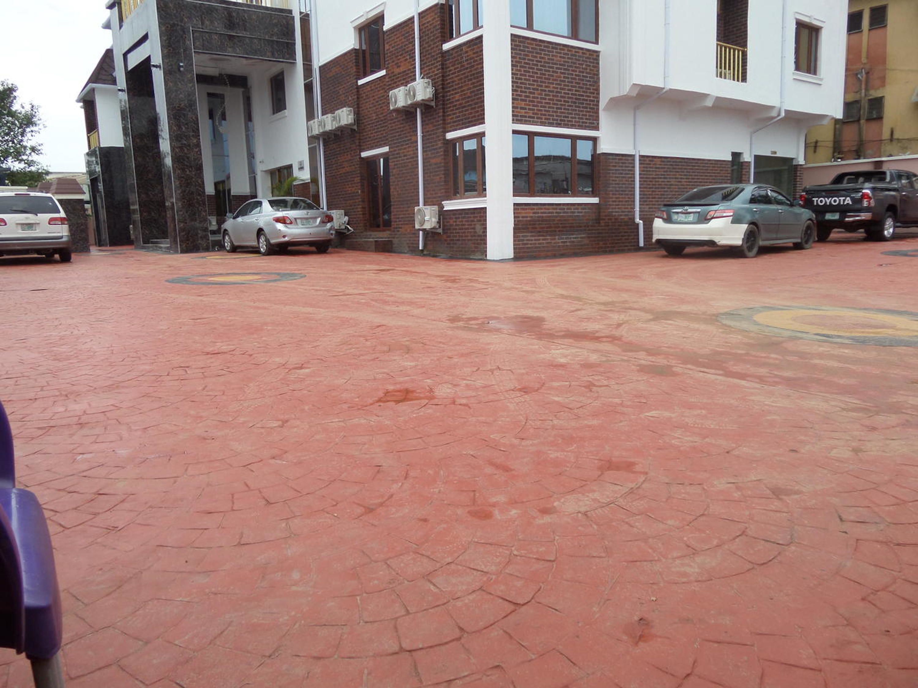 A parking area with a paved surface, a building with a brick facade, and parked cars including a Toyota.