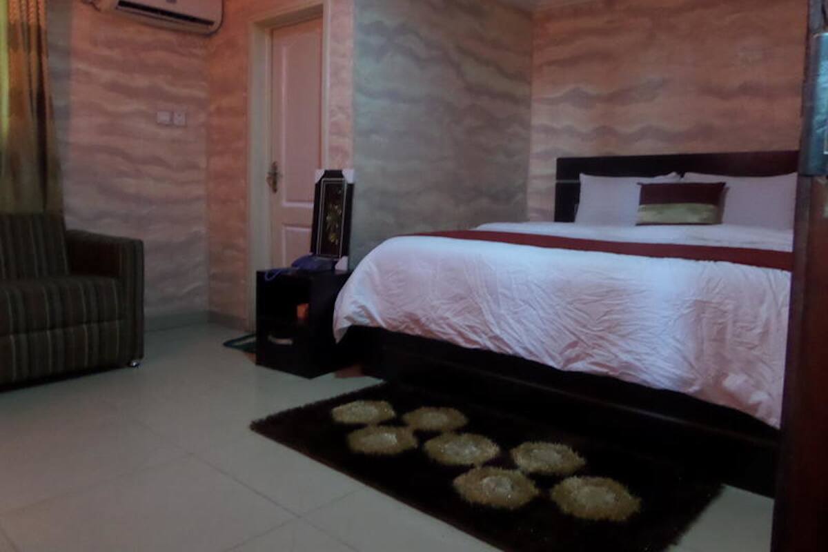 A bedroom with a bed, a chair, and a small table.