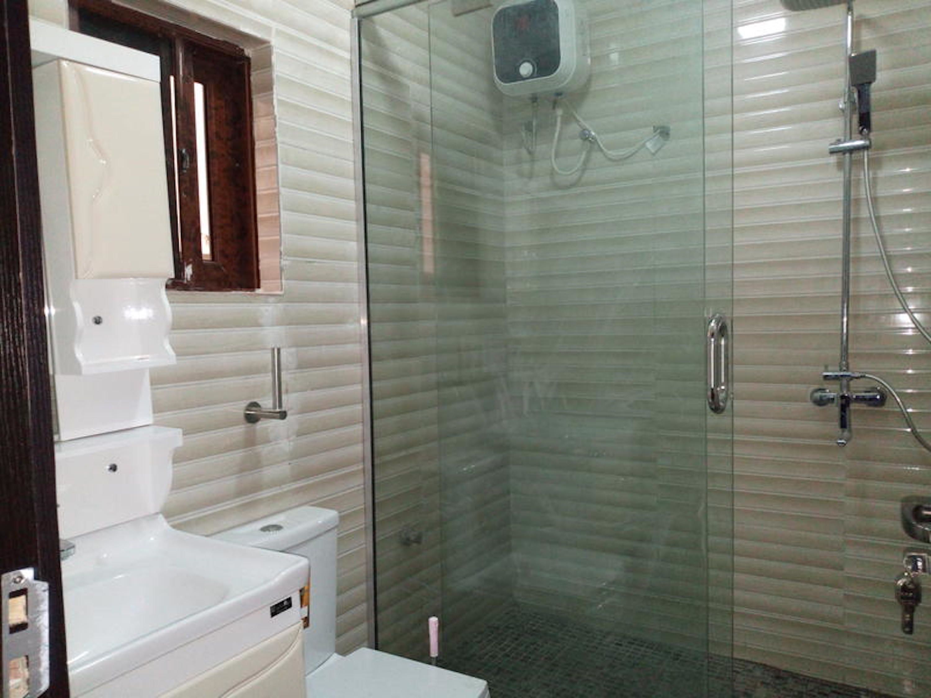 Un baño con cabina de ducha de vidrio, un lavamanos blanco y un inodoro.