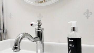A bathroom with a white sink, a chrome faucet, and a soap dispenser.