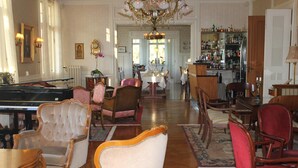 A spacious room with a grand piano, multiple chairs, a dining table, and a bar area with a liquor cabinet.