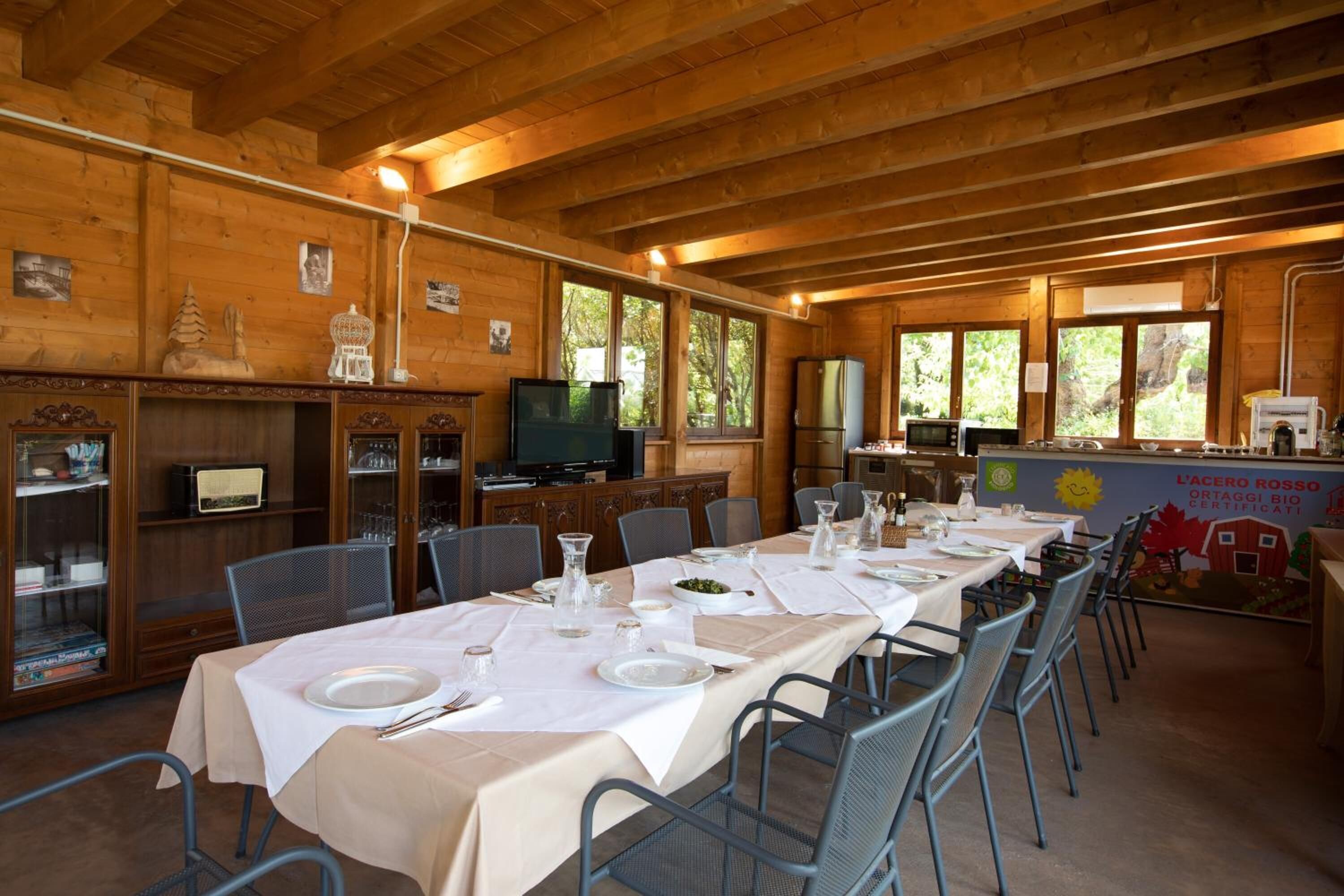 A dining area with long tables set for a meal, wooden walls, and a banner with text.