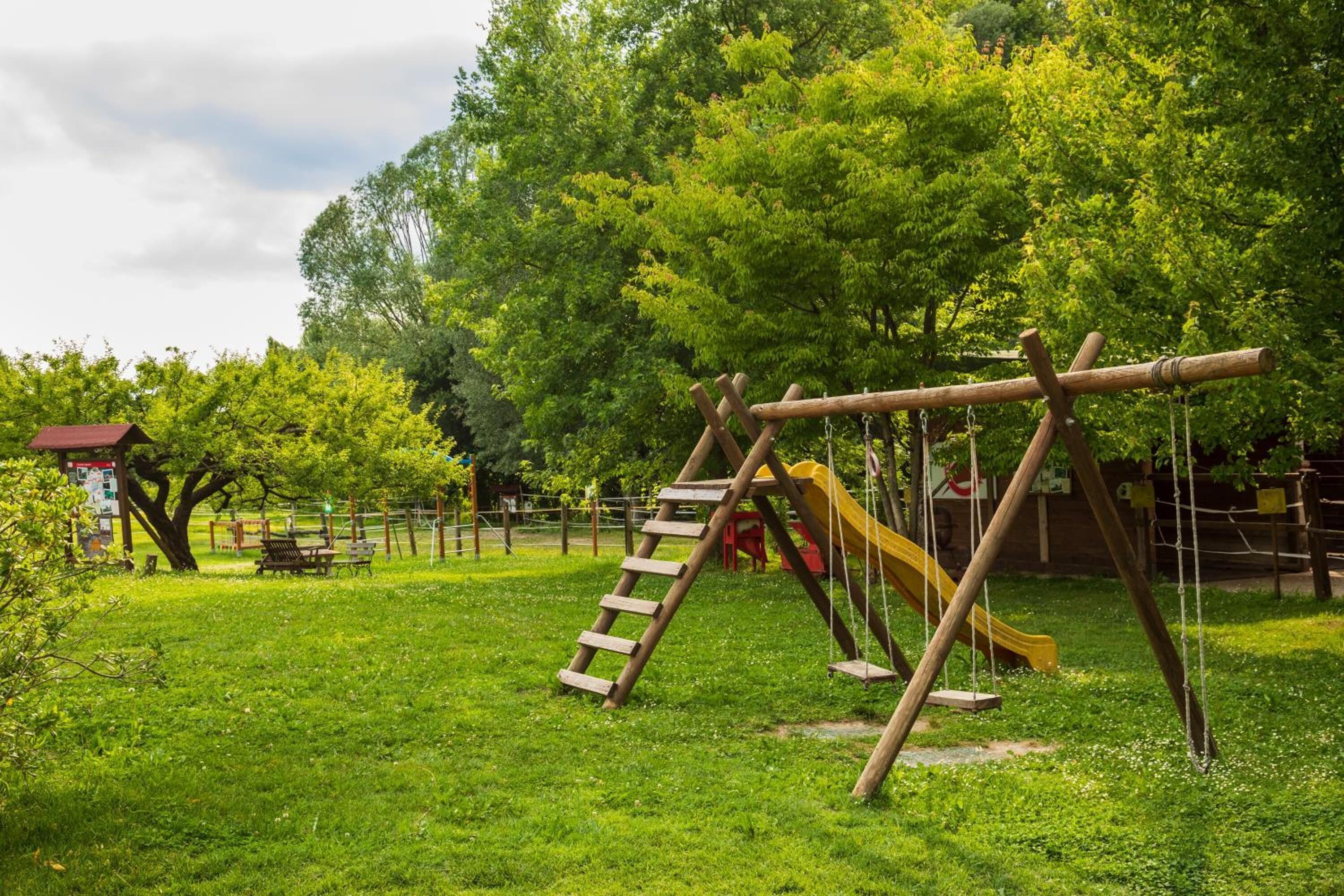A playground with a wooden swing set, a slide, and a ladder.