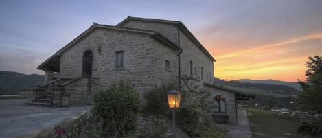 A stone building with a sloped roof, a small porch, and a garden with a stone lantern.