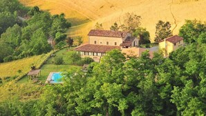 Una amplia casa con piscina, rodeada de vegetación exuberante y colinas ondulantes.
