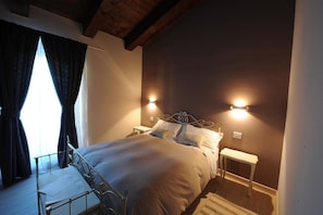 Un dormitorio con cama, mesitas de noche y ventana con cortinas.