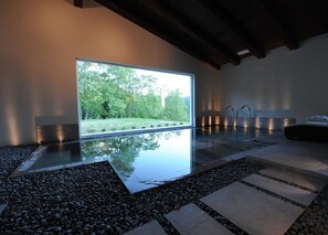 A modern interior with a large window, a reflective water feature, and a stone pathway. - Agriturismo Acero Rosso (Civitella di Romagna)