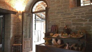 Un interior rústico con paredes de piedra, una silla de madera y una mesa con objetos decorativos.