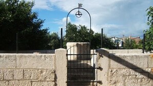 Eine Steinmauer mit einem Metalltor und einem Metallbogen.