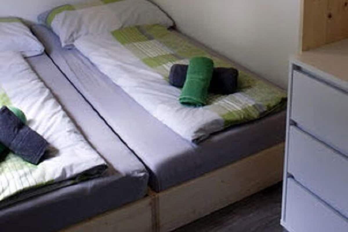 A bedroom with two single beds, a wooden wardrobe, and a painting of a waterfall on the wall.