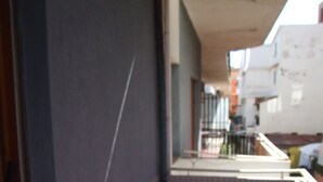 Un corridoio stretto con pareti e pavimento piastrellati, che conduce a una zona con balcone e vista sulla strada.