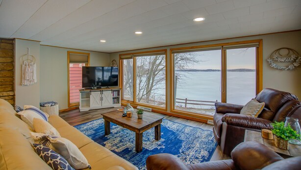 A living room with a large window, a television, a sofa, and a leather couch.