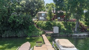 A wooden dock with two boats, a small shed, and a house in the background.